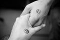 Black and white pictures. Two hands holding each other with yin and yang symbols. Royalty Free Stock Photo