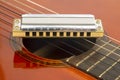 The harmonica rests on the body of a classical guitar. Classical musical wind instrument Royalty Free Stock Photo