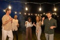 Harmonious Celebration: Multicultural Friends Dancing Under the Evening Garden Lights, group of multi ethnical friends