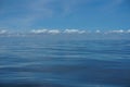 Harmony background scene of gradient blue sky horizon and low raining white cloud above deep blue sea water ripple freezing motion Royalty Free Stock Photo