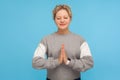 Harmony healing, yoga. Tranquil woman with short curly hair in sweatshirt doing namaste gesture and praying with closed eyes,