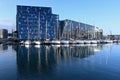 Harpa Concert Hall reflected in calm water of Reykjavik Harbor on sunny morning.