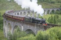 The Harry Potter train or Jacobite steam locomotive,blowing steam,carries tourists across Glenfinnan Viaduct