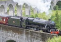 The Harry Potter train or Jacobite steam locomotive,blowing steam,carries tourists across Glenfinnan Viaduct