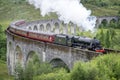 The Harry Potter train or Jacobite steam locomotive,blowing steam,carries tourists across Glenfinnan Viaduct
