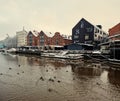 Harsh Baltic winter. Gloomy morning on the shore with authentic houses and ducks swimming in the bay