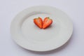 Hart shaped, fresh, organic strawberry halved and decorated on a white plate. Royalty Free Stock Photo