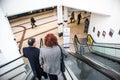 Couple of people traveling down an escalator inside a modern clean building