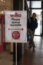 Social Distance information reminder sign for Wilko saying Please Queue Opposite in shopping centre mall
