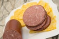 Harvati cheese with sliced spicy sausage served on a cheeseboard with cheese cutters alongside a bottle of red wine with a corkscr Royalty Free Stock Photo