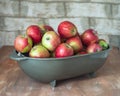 Harvest red and green apples in gray plastic basket on wooden table Royalty Free Stock Photo