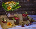 A harvest of ripe cherries in a vintage dish, a bouquet of wildflowers in a vase. Summer still life Royalty Free Stock Photo