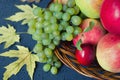 Harvest of ripe fruits - apples, grapes, plums, pears in large wooden plate on black background, decorated autumn maple leaves Royalty Free Stock Photo