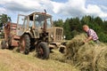 Harvest time hay, russian farmer tractor-driver working in hayfi