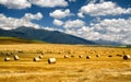 Harvested field with haystacks. Mountains at background Royalty Free Stock Photo
