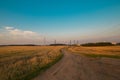Harvested fields with cut straw and electivity power line columns in summer warm sunset evening light Royalty Free Stock Photo