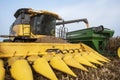Harvester combine dumping corn into grain cart on back of tractor in corn field during harvest