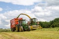 Harvester forager cutting field, loading Silage into a Tractor Trailer