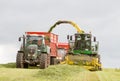 Harvester forager cutting field, loading Silage into a Tractor Trailer Royalty Free Stock Photo