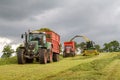 Harvester forager cutting field, loading Silage into a Tractor Trailer