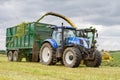 Harvester forager cutting field, loading Silage into a Tractor Trailer