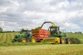 Harvester forager cutting field, loading Silage into a Tractor Trailer Royalty Free Stock Photo