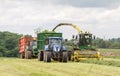 Harvester forager cutting field, loading Silage into a Tractor Trailer