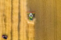 Harvester machine in yellow grain field, aerial top view from drone. Agricultural combine machine harvesting ripe field