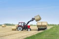 Harvesting of agricultural machinery. The tractor loads bales of hay on the machine after harvesting on a wheat field Royalty Free Stock Photo
