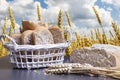 Harvesting crops concept. Fresh bread and wheat on table against golden wheat field and blue sky. Harvest season. Royalty Free Stock Photo