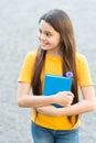 She has got the book she needs. Happy child hold book outdoors. Cute bookworm wear long hair in casual style. School