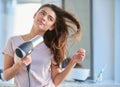 She has the perfect haircare routine. a beautiful young woman blowdrying her hair in the bathroom at home.