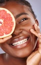 It has some pretty robust skin care benefits. Studio shot of a beautiful young woman holding a halved grapefruit. Royalty Free Stock Photo