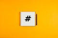 Hashtag icon drawn on a notepad with black pen next to it against yellow background Royalty Free Stock Photo
