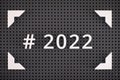 The Hashtag 2022 spelled out with white numbers in a frame on gray pegboard