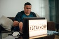 Hashtag stay home. young  hispanic man sitting on couch and working at his laptop during quarantine Royalty Free Stock Photo