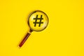 Hashtag symbol under magnifying glass, on yellow background