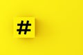 Hashtag symbol on a yellow cube block. Social media communication and trending topic