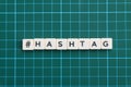 Hashtag word made of square letter word on green square mat background.