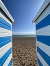 Hastings, East Sussex, UK -03.15.2022: Hastings seafront beach huts on summer day beautiful blue white striped huts on pebble beac Royalty Free Stock Photo