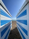 Hastings, East Sussex, UK -03.15.2022: Hastings seafront beach huts on summer day beautiful blue white striped huts on pebble beac Royalty Free Stock Photo