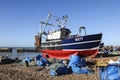 A brightly-coloured Hastings Fishing Boat onshore above the harbour arm.