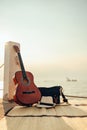 Hat, Bag and Guitar on reed mat near the sea at sunset. Travel, vocation, holiday, summer concept Royalty Free Stock Photo