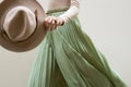 Hat, beige blouse and turqoise pleats skirt on light street backgraund.