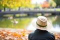 hat by campus pond, ducks nearby, student watching Royalty Free Stock Photo