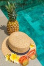 Hat, glasses, pineapple, flowers by the water. Flatley by the pool