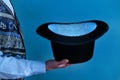 Hat in the hands of a magician on a blue background, close up Royalty Free Stock Photo