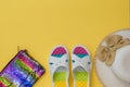 Hat, multi-colored shoes and bag on a yellow background. The concept of summer vacation. Flat lay. Royalty Free Stock Photo