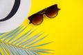 Hat, palm leaf decor, sunglasses on yellow background. Summer, travel concept.