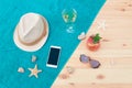 Hat, smartphone, starfishes, seashells, white wine, watermelon lemonade and sunglasses on towel on wooden surface. Top view